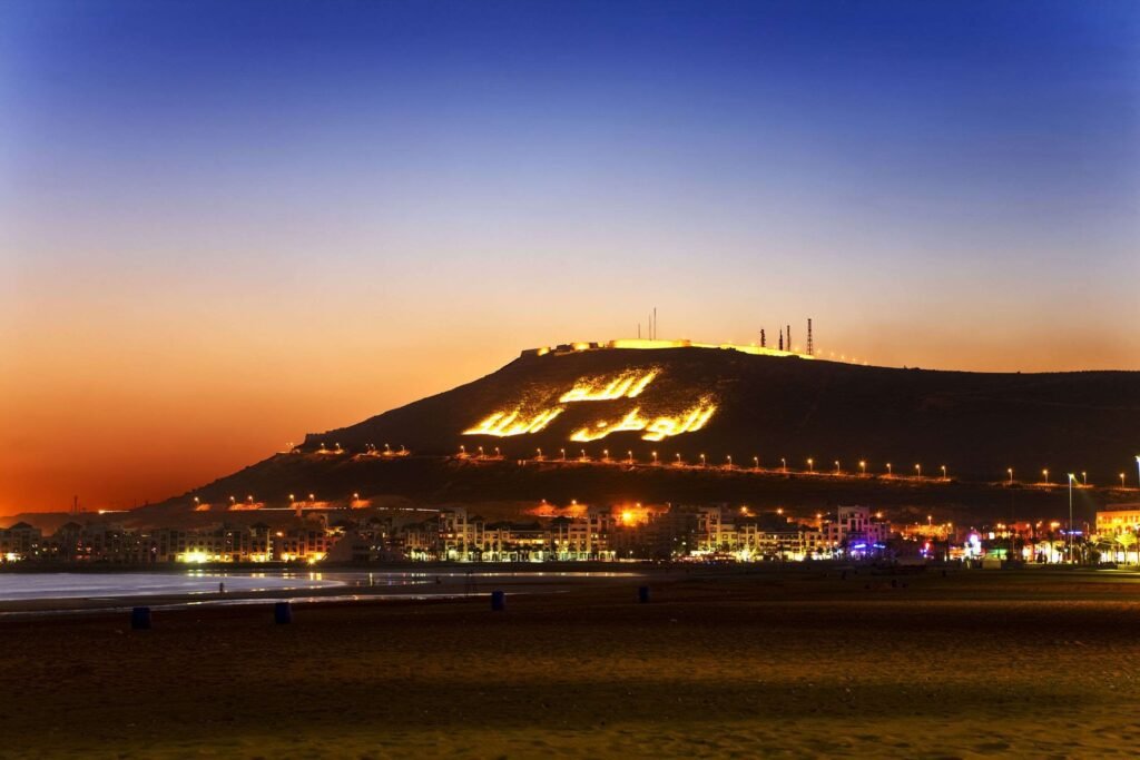 nos destinations – Vue nocturne de la ville d'Agadir et de ses montagnes, offrant une ambiance magique et paisible.
